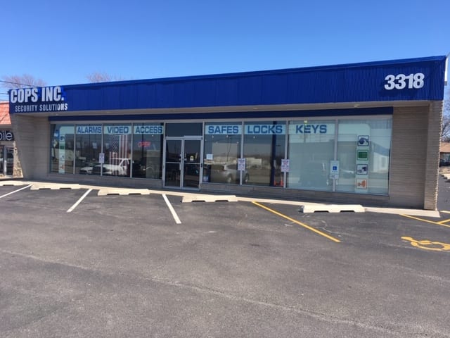 The COPS INC Security Solutions storefront at 3318 N. University St., Peoria — windows reading Alarms, Video, Access, Safes, Locks, Keys